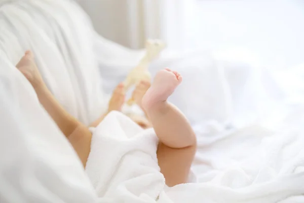 Bebé bonito brincando com os próprios pés depois de tomar banho. Adorável menina bonita envolto em toalhas brancas — Fotografia de Stock