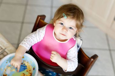 Kaşık püresi ve sebze püresinden yiyen sevimli bir kız bebek. yemek, çocuk, beslenme ve insanlar konsepti