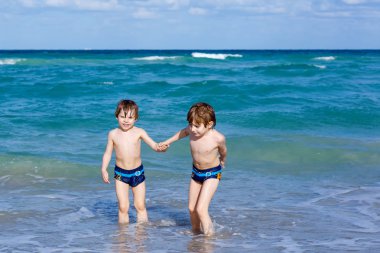 Okyanus plaj üzerinde çalışan iki çocuk çocuklar. Küçük çocuklar eğleniyor