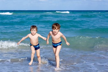Okyanus plaj üzerinde çalışan iki çocuk çocuklar. Küçük çocuklar eğleniyor