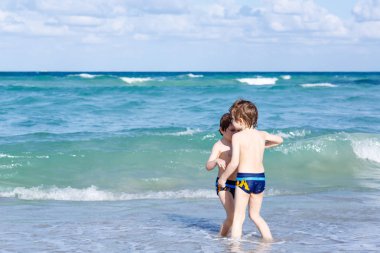 Okyanus plaj üzerinde çalışan iki çocuk çocuklar. Küçük çocuklar eğleniyor