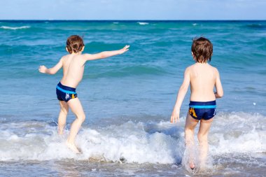 Okyanus plaj üzerinde çalışan iki çocuk çocuklar. Küçük çocuklar eğleniyor