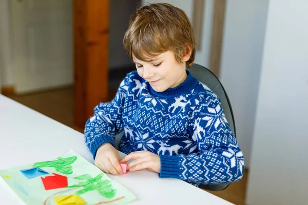 Little kid boy making paper origami tulip flowers for a postcard for mothers day or birthday. Cute child of elementary class school doing handicraft — Stock Photo, Image