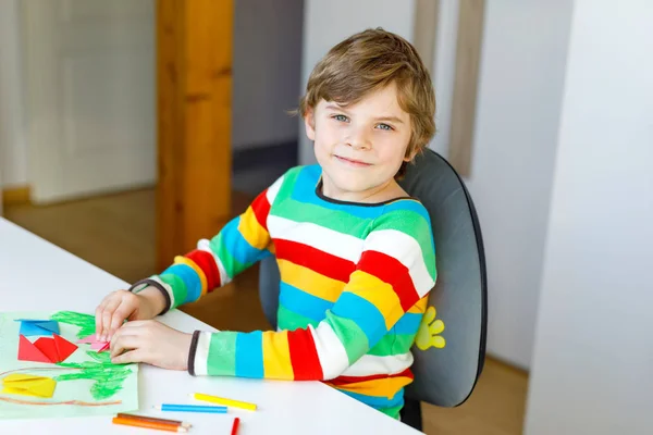 Kleiner Junge bastelt aus Papier Origami-Tulpenblumen für eine Postkarte zum Muttertag oder Geburtstag. Nettes Kind der Grundschule bastelt — Stockfoto