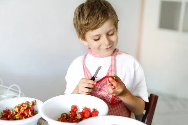 Menino loiro ajudando e fazendo geléia de morango no verão — Fotografia de Stock