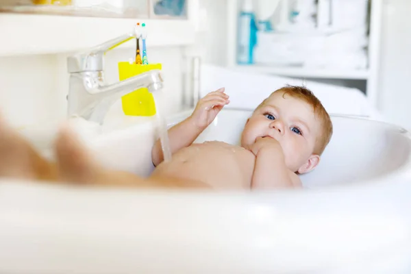 Schattige schattig baby nemen bad in wassen gootsteen en waterkraan pak. — Stockfoto