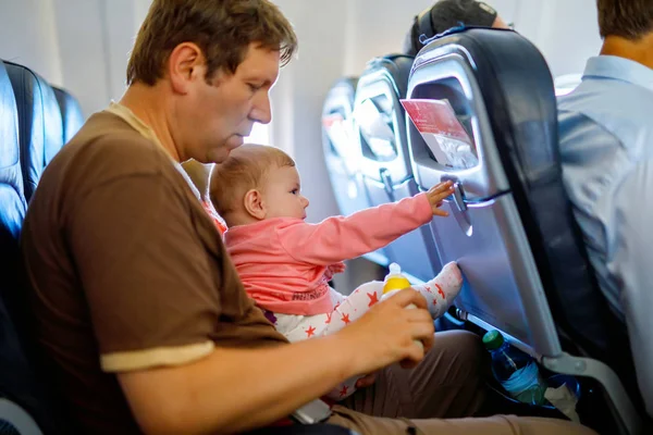 Young tired father and his crying baby daughter during flight on airplane going on vacations — Stock Photo, Image