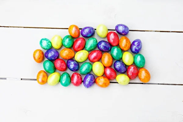 Huevos de Pascua sobre fondo de madera. Huevos coloridos en diferentes colores: rojo, amarillo, naranja, púrpura y verde . — Foto de Stock