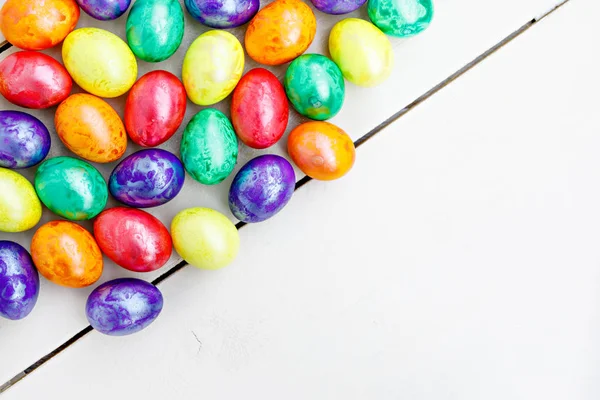 Huevos de Pascua sobre fondo de madera. Huevos coloridos en diferentes colores: rojo, amarillo, naranja, púrpura y verde . — Foto de Stock