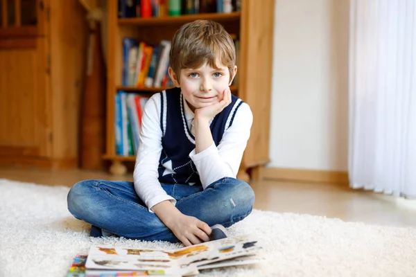 Yurt odasında dergi okuyan sevimli sarışın çocuk. Heyecanlı çocuk yüksek sesle okuyor. — Stok fotoğraf