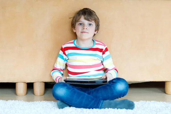 Un ragazzino che fa i compiti con il tablet. Lettura e apprendimento scolastico con il computer, ricerca di informazioni in Internet. — Foto Stock