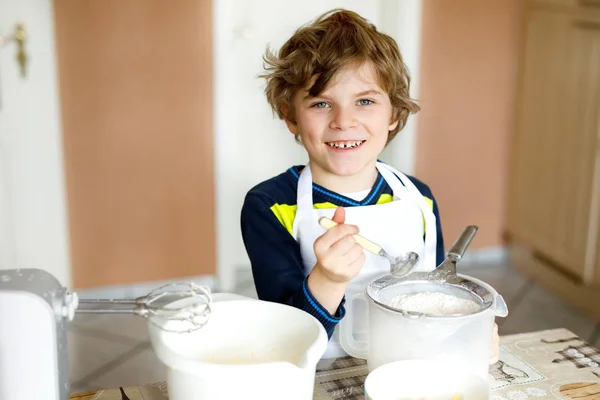 Piękny zabawne blond dziecko chłopczyk pieczenia ciasto czekoladowe i degustacja ciasta w domowa kuchnia — Zdjęcie stockowe