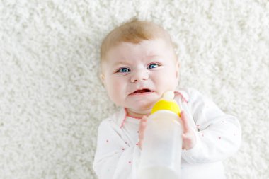 Sevimli, sevimli, doğma büyüme bebek, elinde süt şişesi var ve mama sütü içiyor.