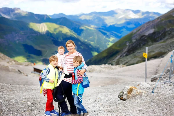 Mère heureuse avec petite fille et deux enfants garçons voyageant dans un sac à dos . — Photo