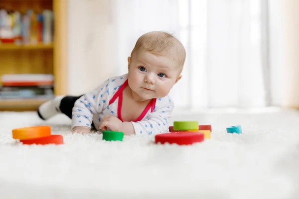 Cute baby girl playing with colorful wooden rattle toy — Stock Photo, Image