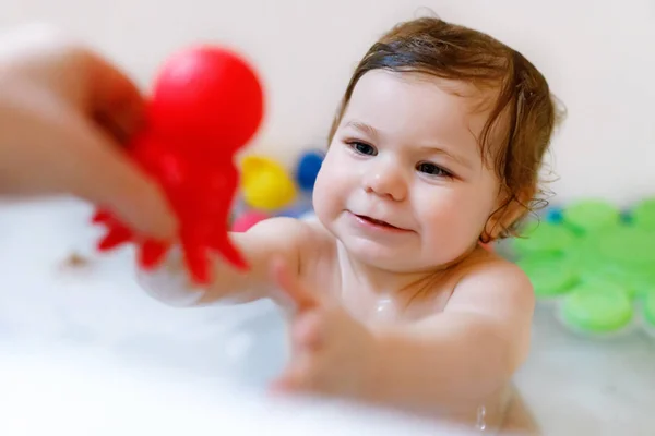 Cute adorable baby girl taking foamy bath in bathtub. Toddler playing with bath rubber toys. — Stock Photo, Image