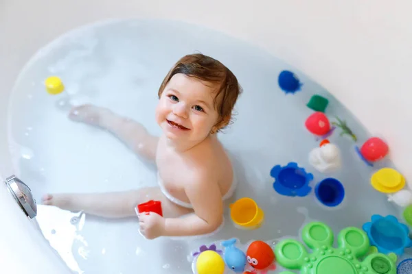 Schattig schattig baby meisje neemt schuimig bad in bad. Peuter spelen met bad rubber speelgoed. — Stockfoto