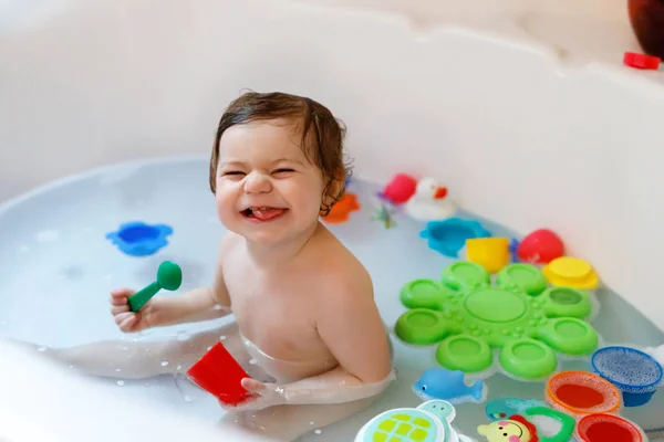 Linda niña adorable tomando baño espumoso en la bañera. Niño jugando con juguetes de goma de baño. —  Fotos de Stock