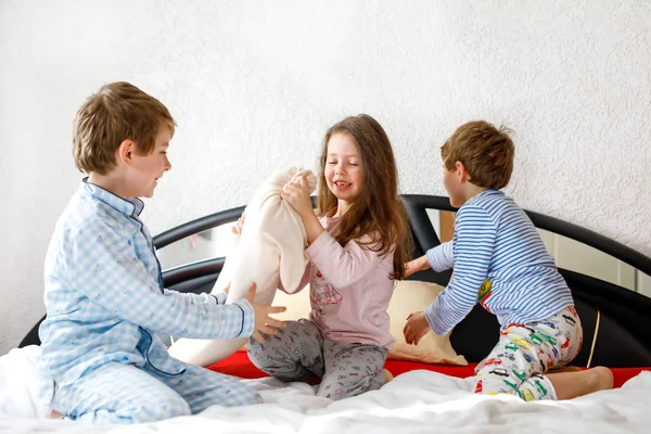 Pijamalı üç mutlu çocuk pijama partisini kutluyor. Anaokulu ve okul çocukları ve kız birlikte eğleniyorlar. — Stok fotoğraf