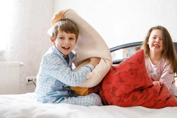 Dos niños felices en pijama celebrando la fiesta de pijama. Preescolar y escolar chico y chica divirtiéndose juntos. — Foto de Stock