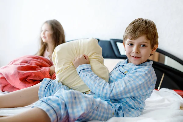 Двоє щасливих дітей у піжамі святкують вечірку піжами. Дошкільний і шкільний хлопчик і дівчинка розважаються разом . — стокове фото