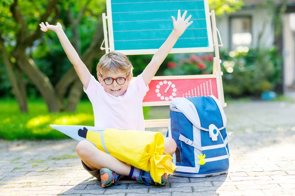 Ευτυχισμένος μικρό αγόρι παιδί με τα γυαλιά που κάθεται από το γραφείο και σακίδιο ή τσάντα — Φωτογραφία Αρχείου