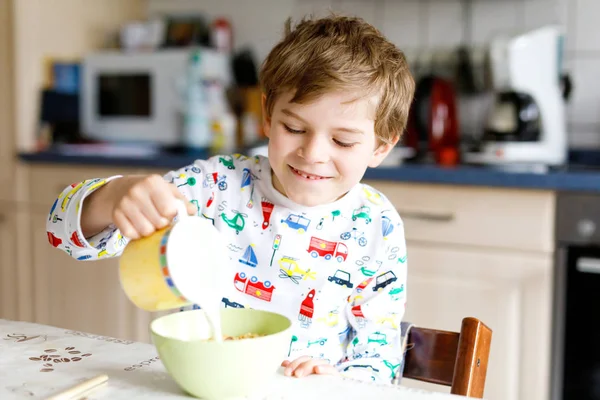 Menino loiro feliz comendo cereais e leite no café da manhã ou almoço . — Fotografia de Stock