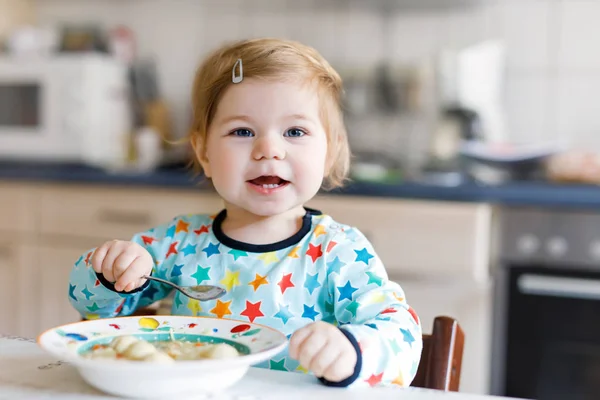 Imádnivaló baba lány kanál zöldség tészta leves elfogyasztása. élelmiszer-, gyermek-, takarmányozási- és emberek koncepció — Stock Fotó