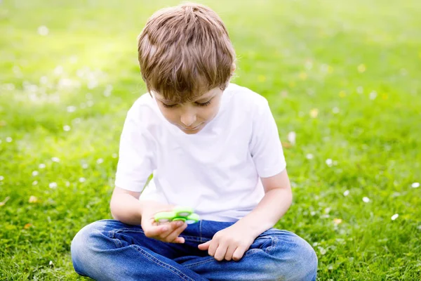 Menino da escola brincando com Tri Fidget Hand Spinner ao ar livre — Fotografia de Stock