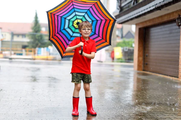 Petit garçon portant des bottes de pluie rouge et marchant avec parapluie — Photo