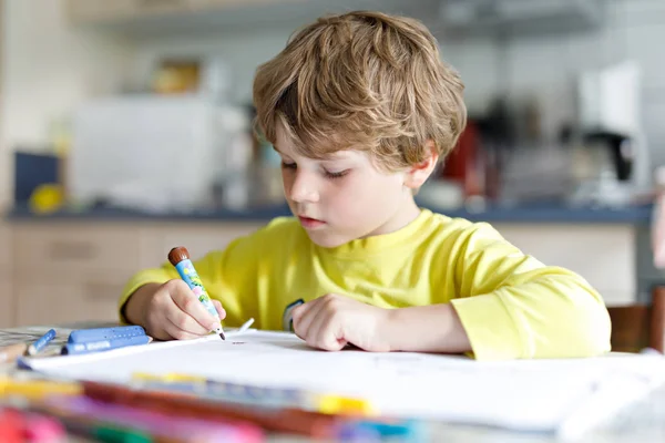 Trött liten pojke hemma att göra läxor skriva brev med färgglada pennor — Stockfoto
