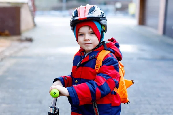 Cute little preschool kid boy riding on scooter riding to school. — Stock Photo, Image