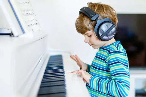 Красивый маленький мальчик играет на пианино в гостиной или музыкальной школе — стоковое фото