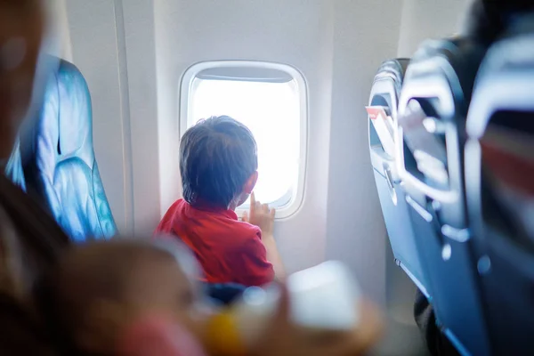 在飞机上飞行的小男孩看在飞机窗口外面. — 图库照片