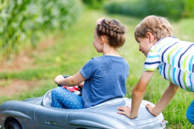 Büyük eski oyuncak araba yaz bahçesinde, açık ile oynarken iki mutlu çocuk