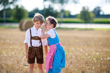 İki çocuk, erkek ve kız ile saman balya buğday alanında geleneksel Bavyera kostümleri