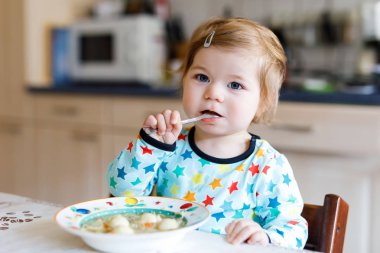 Adorable baby girl eating from spoon vegetable noodle soup. food, child, feeding and people concept clipart