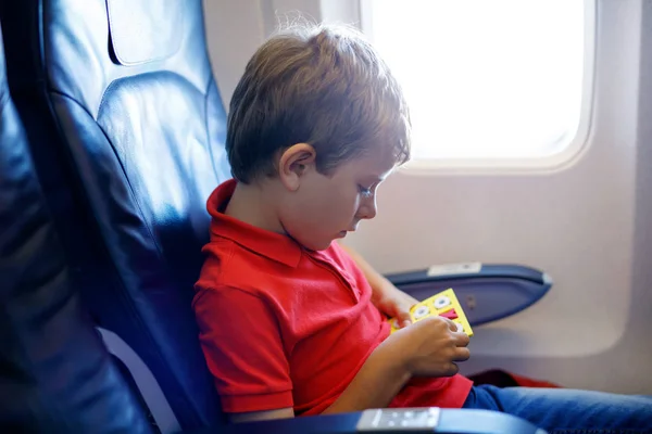 Little kid boy playing tic tac toe game during flight on airplane. — Stock Photo, Image