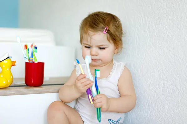 Маленькая девочка держит зубную щетку и чистит первые зубы. Малыш учится чистить молочный зуб. — стоковое фото