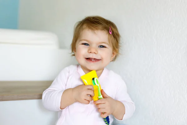 Niña sosteniendo cepillo de dientes y cepillándose los primeros dientes. Niños pequeños aprendiendo a limpiar los dientes de leche. — Foto de Stock