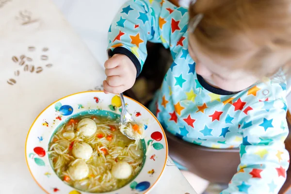Menina adorável comendo de sopa de macarrão vegetal colher. conceito de comida, criança, alimentação e pessoas — Fotografia de Stock