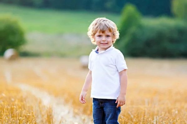 Heureux garçon blond enfant profitant du coucher de soleil dans le champ de blé . — Photo