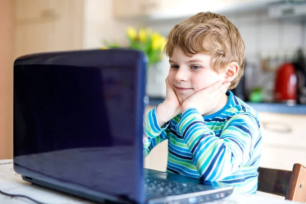 Niño de la escuela haciendo deberes escolares en la computadora. Niño divirtiéndose con el aprendizaje en el portátil PC . — Foto de Stock