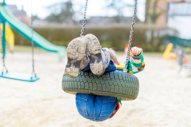 Komik çocuk dışarıda zincirli salıncakla eğleniyor.