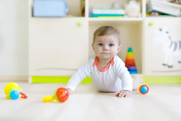 Χαριτωμένο μωρό κορίτσι παίζει με τα πολύχρωμα κουδουνίστρα παιχνίδια — Φωτογραφία Αρχείου