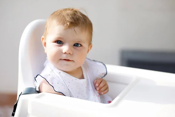 Portret van een schattig klein meisje zittend in een kinderstoel en wachtend op eten — Stockfoto