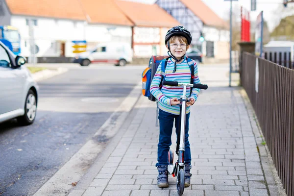 Niño en casco montado con su scooter en la ciudad —  Fotos de Stock