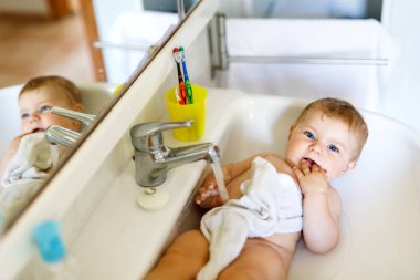 Alarak şirin bebek yıkama lavabo banyo ve musluk suyu yakala.
