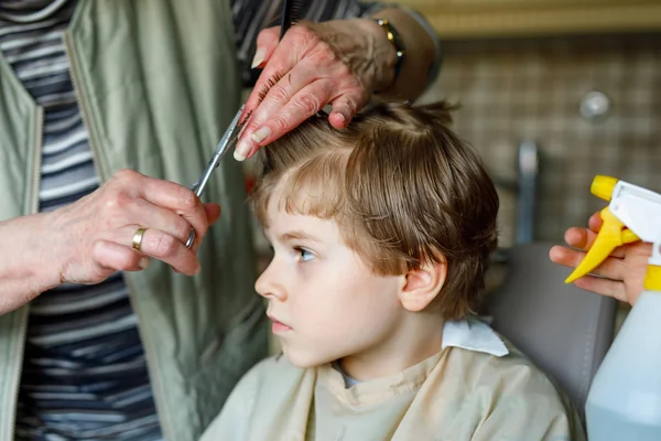 Menino bonito com cabelos loiros recebendo seu primeiro corte de cabelo . — Fotografia de Stock