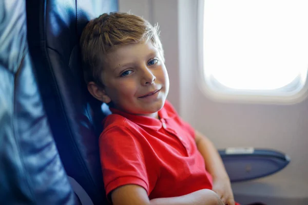 Kleine jongen jongen op zoek buiten vliegtuig venster tijdens vlucht op vliegtuig. — Stockfoto